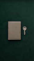 Beige leather notebook with silver key on dark teal background, flat lay composition for business, security, and organization concepts.