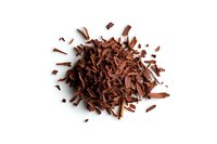 Pile of grated dark chocolate shavings and curls isolated on white background, ready for cooking, baking, or dessert decoration. Perfect for culinary designs.