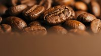 Roasted coffee beans close-up macro shot with rich brown colors and detailed texture for cafe branding and beverage marketing materials.