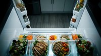 Overhead view of open refrigerator displaying organized meal prep containers with grilled proteins, vegetables, and grains for weekly nutrition planning and healthy eating routines.
