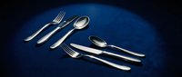 Elegant silver cutlery set arranged on deep blue surface, featuring polished forks, spoons and knives for fine dining and upscale table settings.