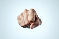 Dramatic close-up of clenched fist pointing forward against light background, symbolizing power, determination, strength and confrontation in business or personal concept.