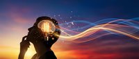 Human silhouette with glowing brain and flowing energy waves against dramatic sunset sky representing artificial intelligence and mental power.
