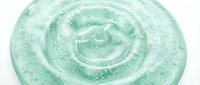 Close-up of translucent green gel with swirled texture and sparkle particles, isolated on white background for cosmetic, skincare product design and packaging mockups.