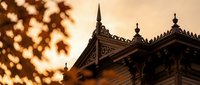 Ornate wooden architecture detail with decorative carved elements and traditional roofline against warm sunset sky creating atmospheric heritage ambiance.