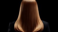 Straight honey blonde hair from back view on black background shows smooth, glossy texture and professional salon styling result. Haircare and beauty concept.