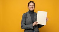 Professional businesswoman in gray suit holding blank paper document against vibrant yellow background for corporate presentations and marketing materials.