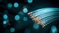 Glowing fiber optic cables with illuminated tips against dark background with blue bokeh lights, modern technology and digital communication concept.