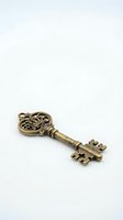 Antique brass skeleton key with ornate decorative head and serrated shaft isolated on white background, suitable for vintage design, steampunk projects, and decorative applications.