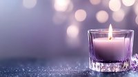 Purple candle burning in crystal glass holder with soft bokeh lights creating romantic spa atmosphere for relaxation and meditation rituals.
