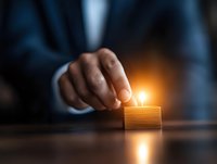 Businessman placing glowing light on wooden block in dark room, representing innovative solutions and business growth opportunities in leadership concept.