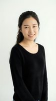 Young Asian woman smiling confidently in black sweater against white background, studio portrait for business or lifestyle use.