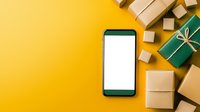 Modern smartphone with blank white screen mockup surrounded by wrapped gift boxes and packages on vibrant yellow background, flat lay composition.