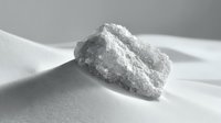 White crystalline powder or substance on light surface in macro photography with dramatic shadows, minimalist composition for pharmaceutical or chemical concept.