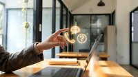 Professional hand selecting golden star rating icon in modern office workspace with laptop and natural lighting for customer satisfaction feedback.