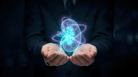 Businessman hands presenting glowing atomic structure with orbiting electrons on dark background for science technology concepts.