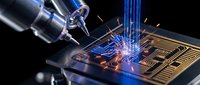 Precision laser welding machine creating sparks on electronic circuit board in high-tech manufacturing facility for industrial automation and technology production.