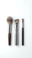 Three makeup brushes with natural bristles and metallic ferrules isolated on white background, featuring round, flat, and angled brush heads for foundation, contouring, and eyeshadow application.