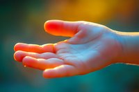 Open palm illuminated by warm orange and cool blue light against blurred background creates ethereal mood for spiritual and wellness concepts.