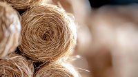 Natural jute rope coils stacked together showing organic fiber texture and rustic brown color for craft projects and nautical decoration.