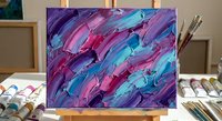 Abstract acrylic painting with purple, pink and turquoise brushstrokes on canvas displayed on wooden easel in art studio with paintbrushes and palette.
