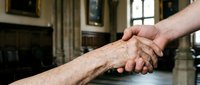 Two people shaking hands in an indoor setting, symbolizing agreement, partnership, trust, and professional collaboration between individuals.