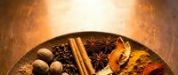 Warm spices including nutmeg, cinnamon sticks, star anise, and turmeric arranged on wooden surface for cooking and culinary design projects.