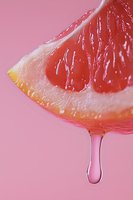 Fresh grapefruit slice with juice drop falling, extreme close up macro shot on pink background. Natural citrus fruit with vibrant texture and juicy pulp.