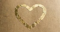 Heart shape drawn in wet sand on beach shore with gentle waves washing over romantic symbol for love and affection concepts.