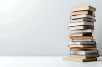 Stack of hardcover books in beige and brown tones arranged on white table against light gray wall background, creating minimalist composition for education concepts.