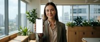 Young Caucasian businesswoman in suit holding smartphone with blank white screen mockup in modern office, smiling confidently at camera.