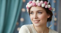 Young Caucasian woman with pink and white flower crown smiling warmly in cozy indoor setting with soft lighting and teal curtains background.