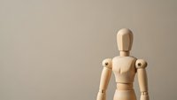 Wooden articulated drawing mannequin figure on neutral beige background for art reference, anatomy study, and creative design projects.