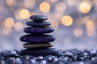 Balanced black spa stones pyramid with purple glitter on wet surface against soft bokeh lights background creating zen and relaxation atmosphere.