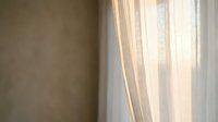 Sunlight streams through sheer white curtains into a minimalist room with neutral beige walls, creating soft shadows and a serene, peaceful atmosphere ideal for wellness and lifestyle content.