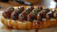 Grilled sausage links on toasted bun with herbs and spices, drizzled with sauce, close up view showing juicy meat texture and caramelized surface.