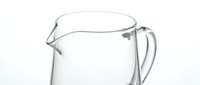 Clear glass water pitcher with handle and spout isolated on white background for kitchen and dining design projects.