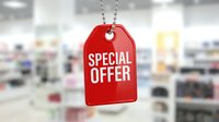 Red special offer price tag hanging on chain in blurred retail store background, discount promotion concept for shopping and sales.