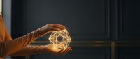 Hands holding glowing geometric wireframe structure against dark background, representing innovation, technology, and creative solutions for business and design projects.