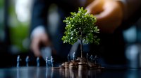 Small green tree growing from stack of coins with miniature business figures, symbolizing sustainable financial growth and environmental investment strategies.
