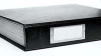Closed black office binder with blank white label on spine, isolated on white background, ready for design mockups, branding, and organizational storage solutions.