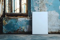 Blank white canvas mockup against weathered turquoise wall with vintage window, grunge texture and peeling paint. Urban decay atmosphere for art display.