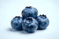 Fresh ripe blueberries with natural bloom coating on white background, macro close up view showing texture and details of organic berries for healthy eating.