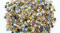 Scattered jigsaw puzzle pieces in various colors and patterns spread across white background, representing leisure activity, entertainment, games, and recreational hobbies.