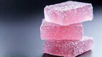 Pink Turkish delight candy pieces stacked with powdered sugar coating on gradient background for confectionery and dessert concepts.