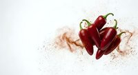 Fresh red jalapeno peppers with scattered spice powder on white background, bold food styling for culinary and packaging design.