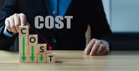 Businessman arranging wooden blocks spelling COST with downward arrows showing expense reduction and budget optimization strategies in corporate office.