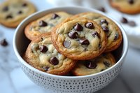 Fresh baked chocolate chip cookies with crispy edges and soft centers served in white ceramic bowl, close up view of homemade classic dessert treats.