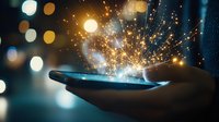 Magical light sparkles emerging from smartphone screen held in dark with glowing bokeh background, creating ethereal digital transformation concept.