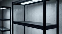 Modern black metal shelving unit with clean lines against concrete wall for contemporary interior design and storage solutions.